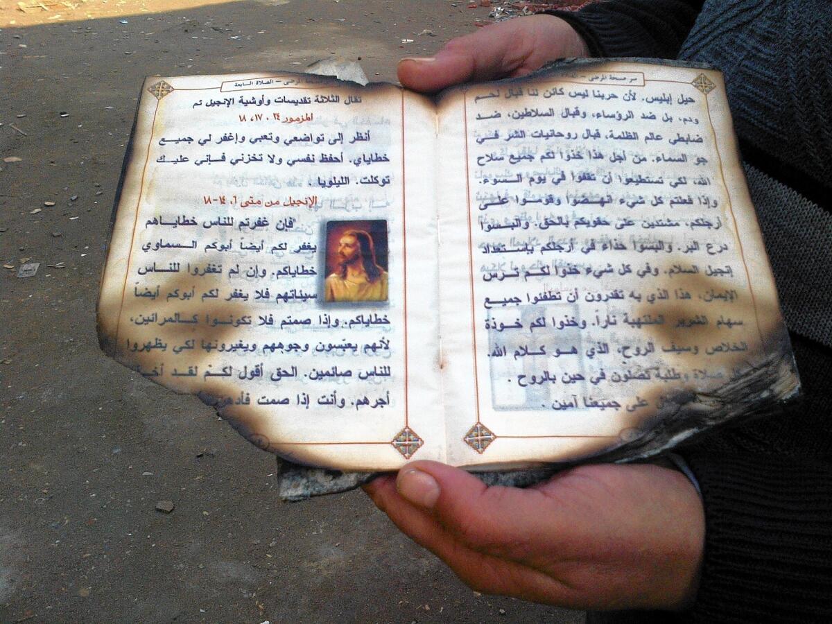 An Egyptian parishioner holds a Coptic prayer book salvaged from the Church of the Archangel Michael in Kerdasa, which was attacked in August.