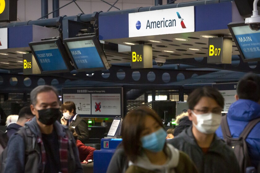 FILE - Travelers wearing face masks line up to check in for an American Airlines flight to Los Angeles at Beijing Capital International Airport in Beijing, Thursday, Jan. 30, 2020. U.S. airlines say China has blocked more than a dozen recent and future flights from entering the country, which has been tightening already-strict COVID-19 travel restrictions. China ordered the cancellations after some passengers tested positive for COVID-19 on flights that arrived in China in late Dec. 2021, according to industry officials. (AP Photo/Mark Schiefelbein, File)