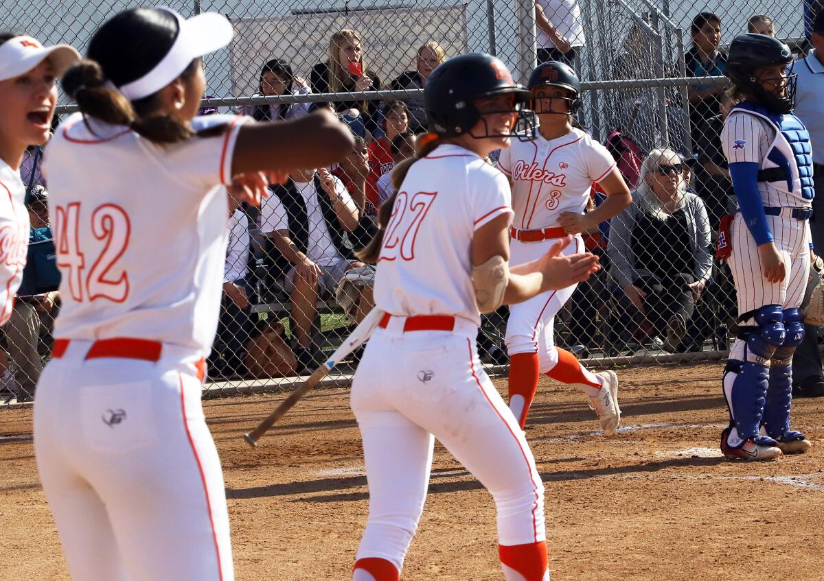 Huntington Beach's softball team cheers as Ashley Long (3) runs in to score on Preslee Brower's triple against Los Alamitos.