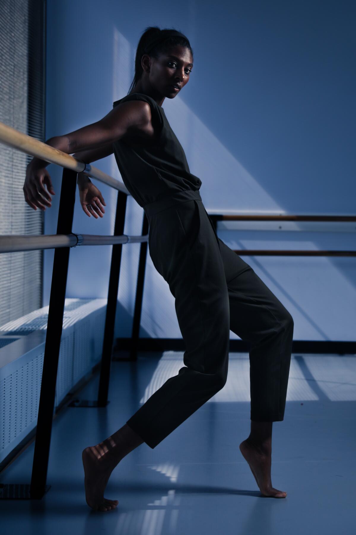 Choreographer Micaela Taylor with her arms draped behind her over a dance barre.