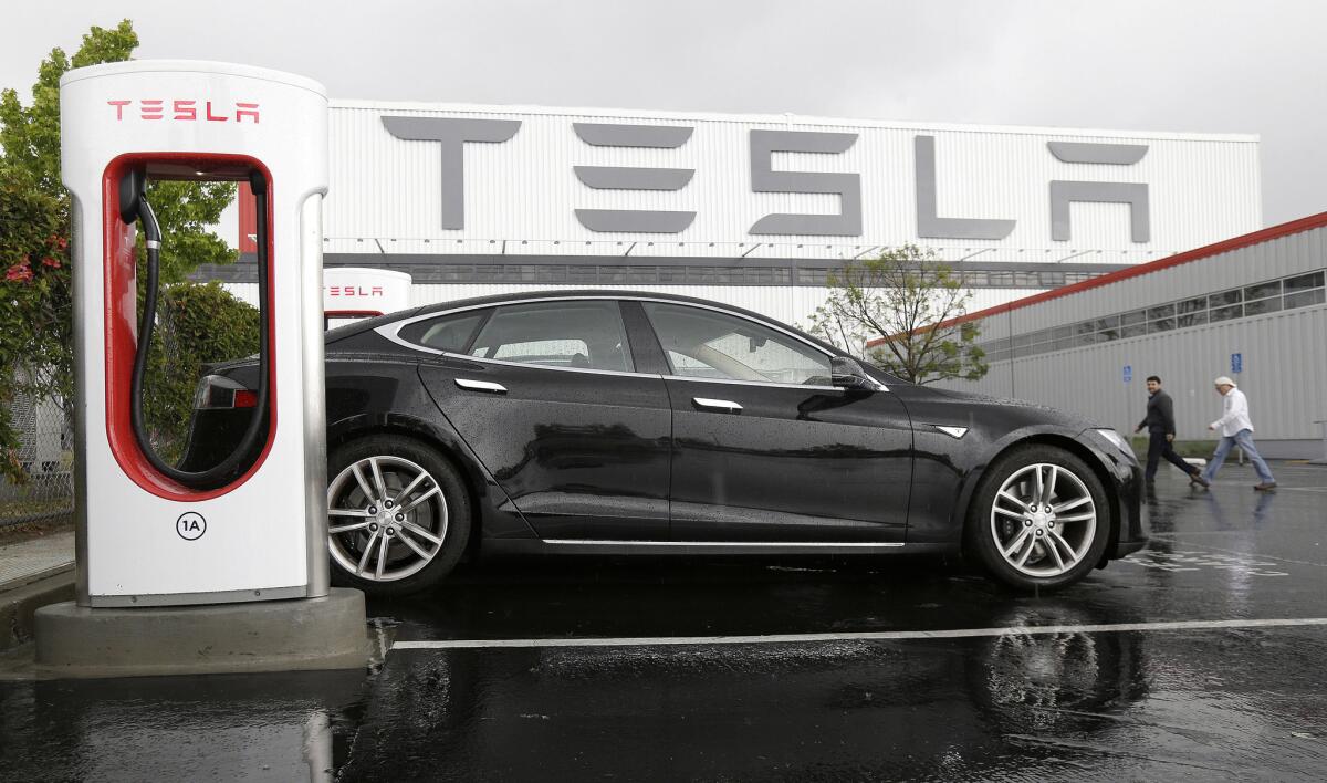 A Tesla vehicle is parked at a charging station outside of the Tesla factory in Fremont, Calif.