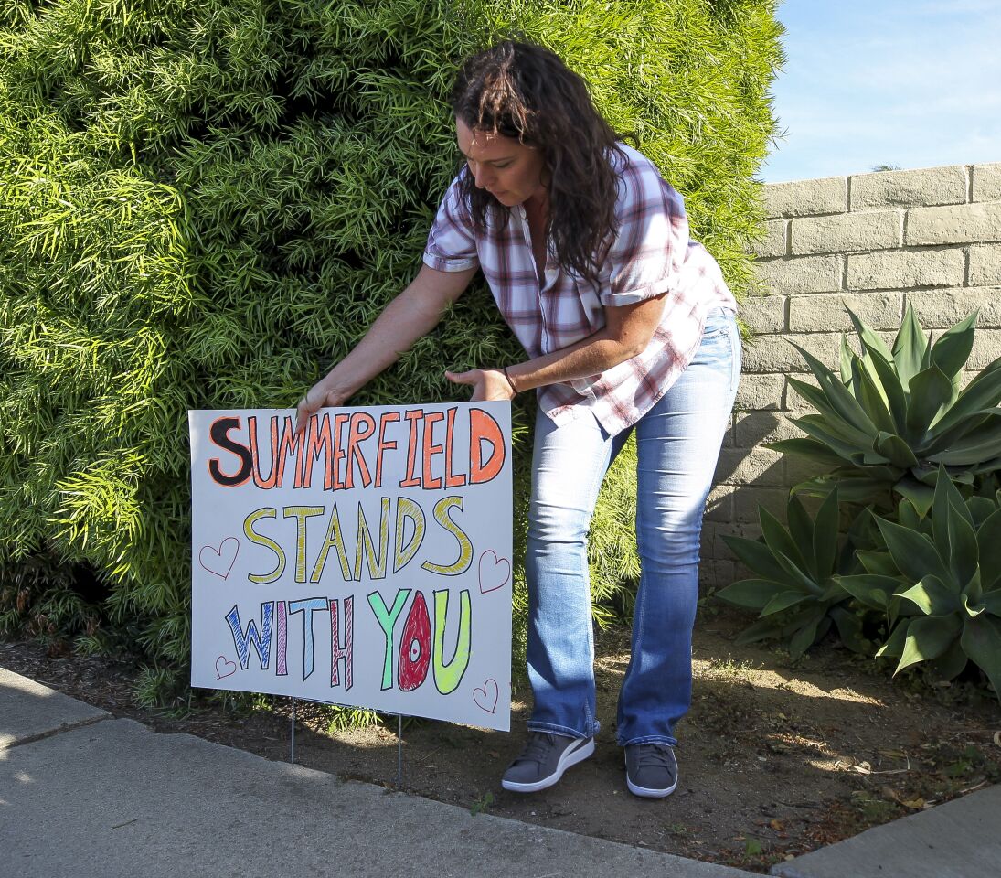 Stacey Cavalieri places a sign near Chabad of Poway, where a man with a gun shot multiple people inside the synagogue, killing one, in Poway on Saturday, April 27, 2019 in Poway, California. Summerfield is the name of the neighborhood adjacent to the synagogue.