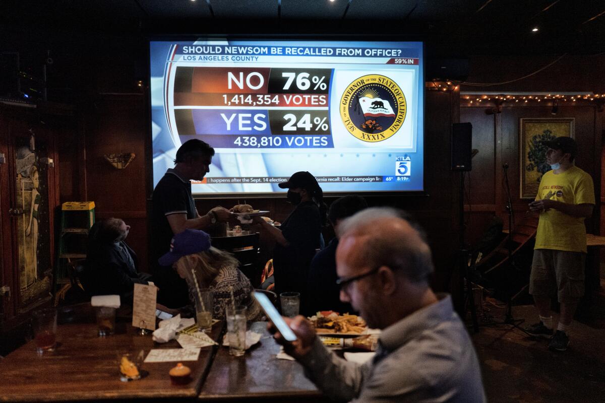 A big screen shows vote numbers while people eat in a restaurant..
