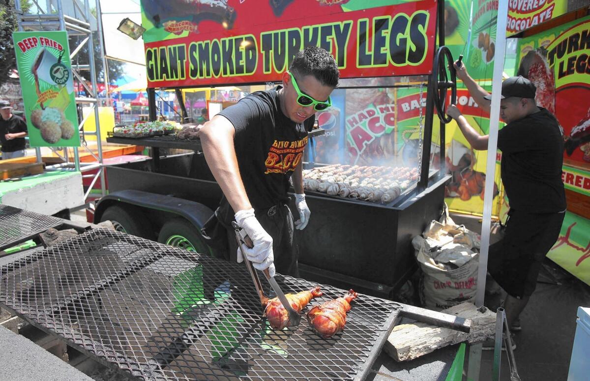 A cook prepares the giant smoked turkey legs at the 2015 Orange County Fair.