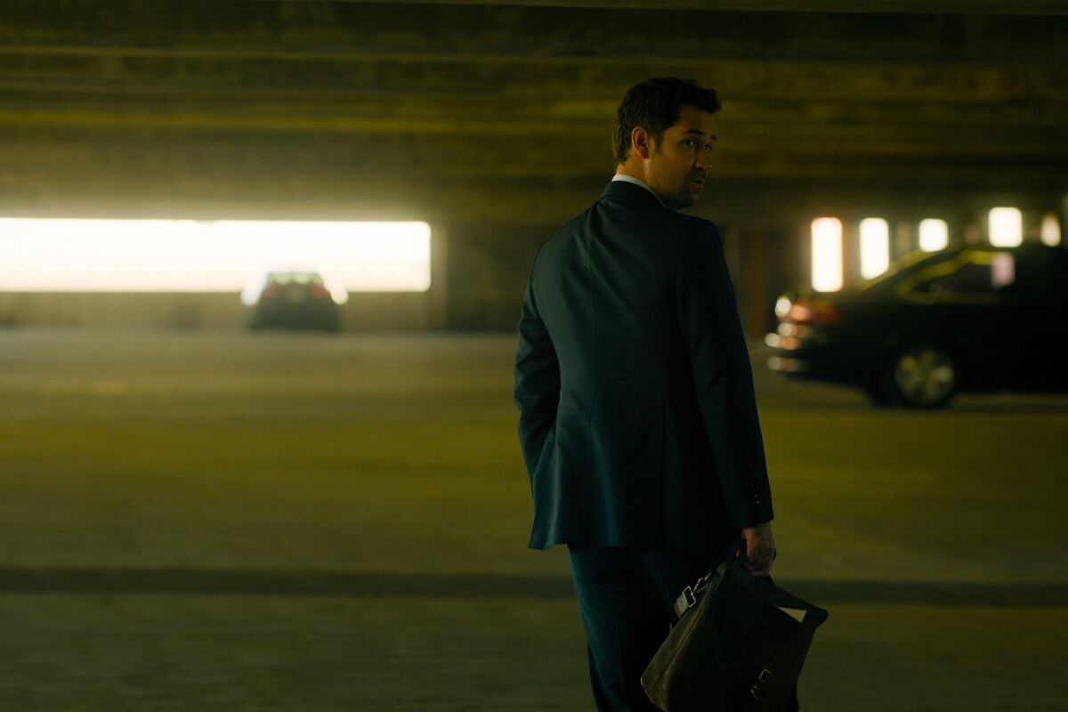 A man walks in a dark parking garage.