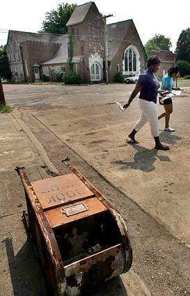 Constance Carter, left, 19, and Panedra Ferguson, 20, walk past a fallen book return box as they go home from school. The book return lays next to the closed Shaw Library, one of 10 in Bolivar County, Miss. Arsonists set fire to the library twice in the mostly black town of Shaw, and every book was destroyed. A second branch in another town was also burned. No arrests have been made.