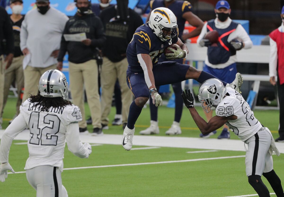 Chargers running back Joshua Kelley tries to leap over oncoming Las Vegas Raiders free safety Lamarcus Joyner.