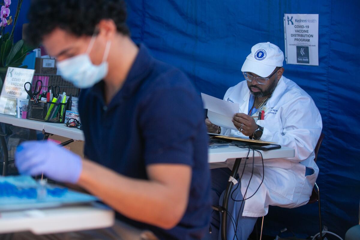 Dr. Jerry P. Abraham, the director of the vaccination center at Kedren Health, works at his desk.