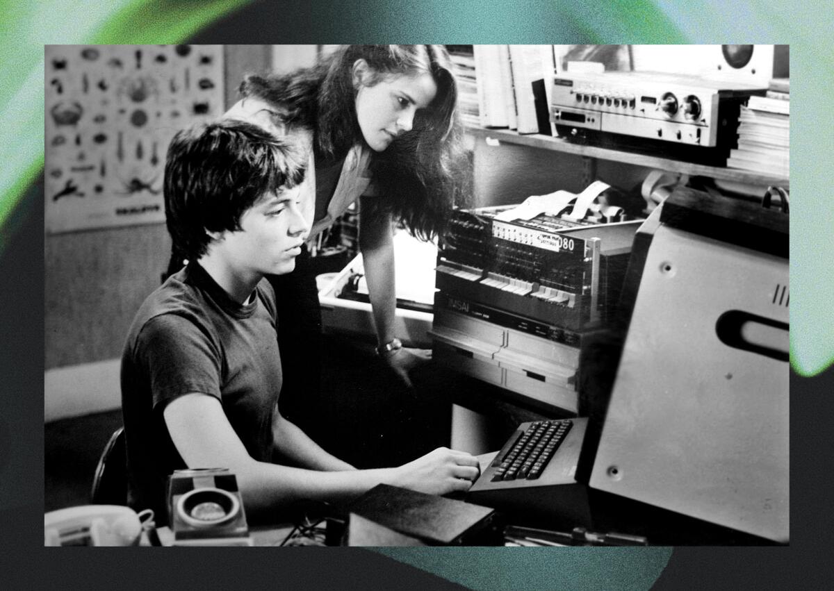Um adolescente sentado em frente a um computador com uma adolescente inclinada sobre ele para olhar a tela em uma cena de "Jogos de guerra."
