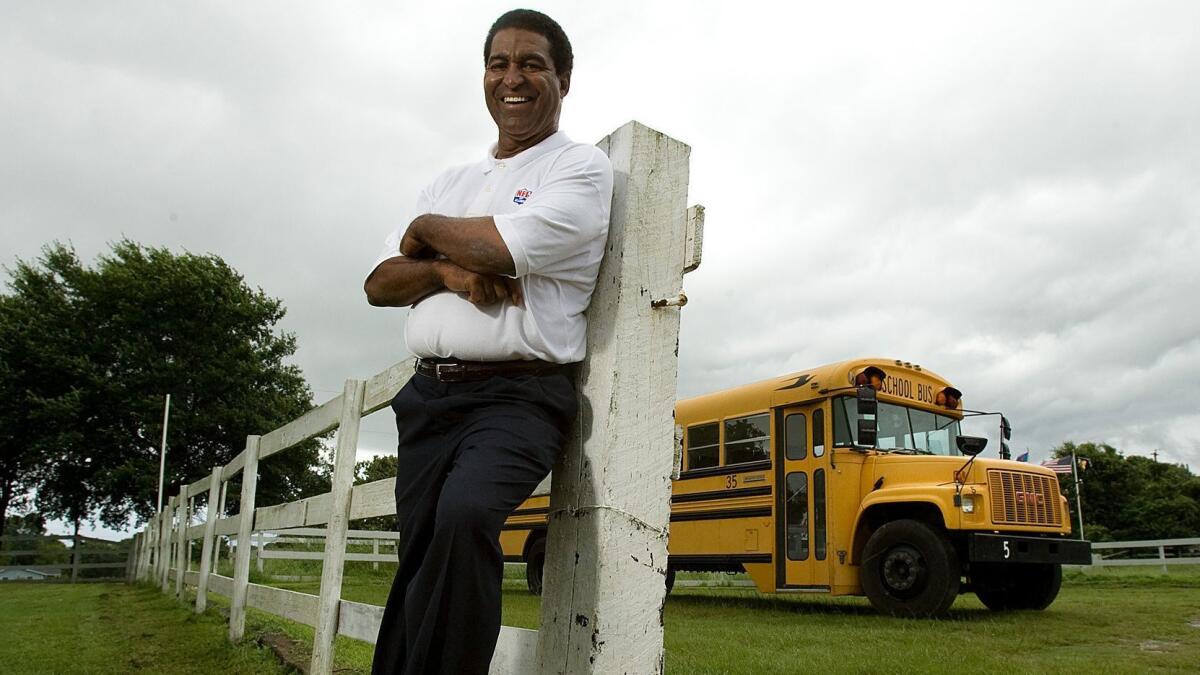 Former Rams linebacker Isiah Robertson poses in front of a fence and a school bus at his Texas rehab center in 2007