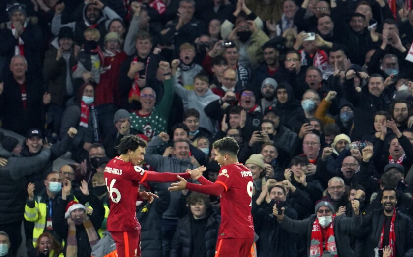 Liverpool's Trent Alexander-Arnold, left, celebrates with Liverpool's Roberto Firmino after scoring his side's third goal during the English Premier League soccer match between Liverpool and Newcastle United at Anfield stadium in Liverpool, England, Thursday, Dec. 16, 2021. (AP Photo/Jon Super)