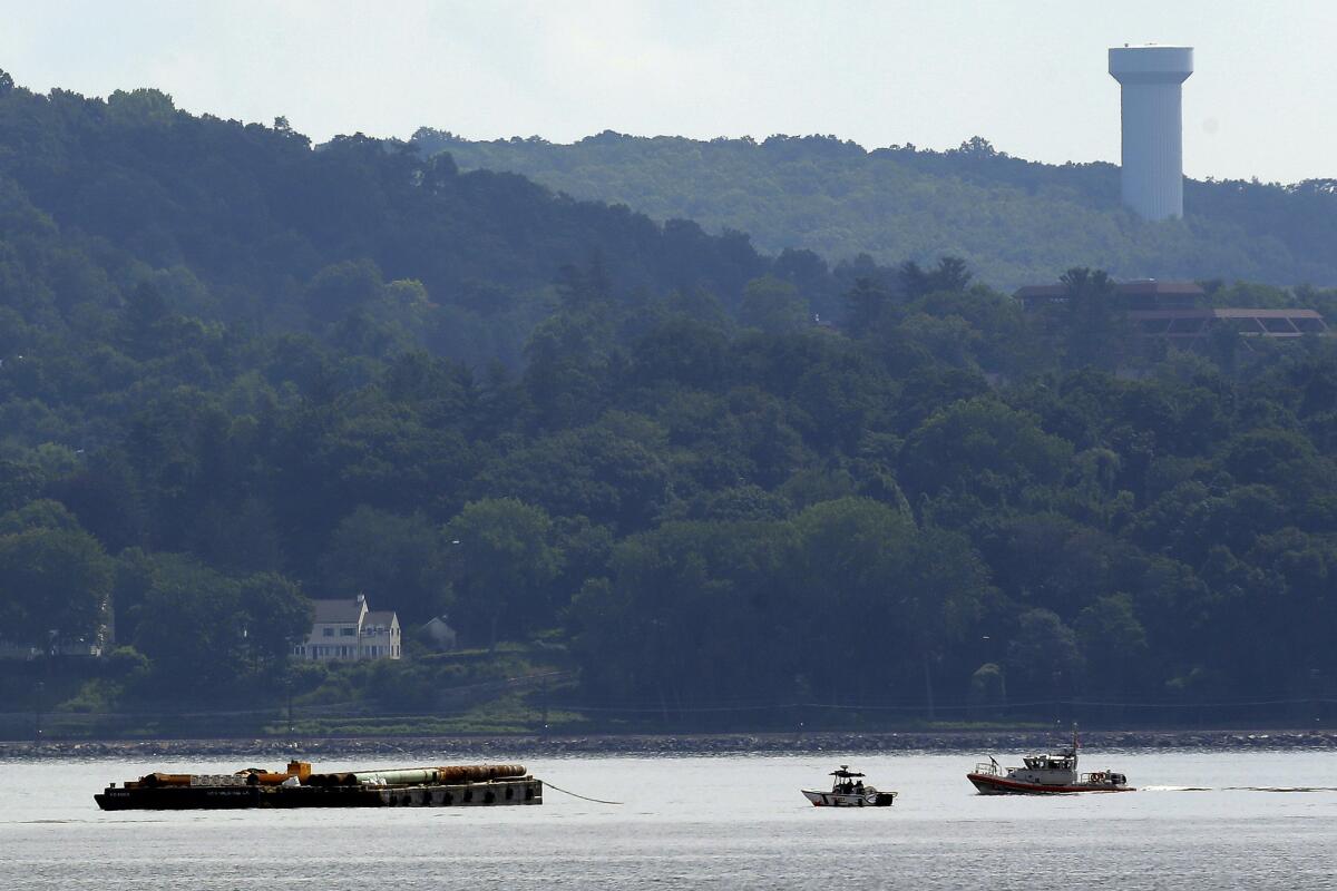 Rescue workers on boats search near a construction barge on the Hudson River for two people who fell into the water during a boat crash. A woman's body has been recovered.