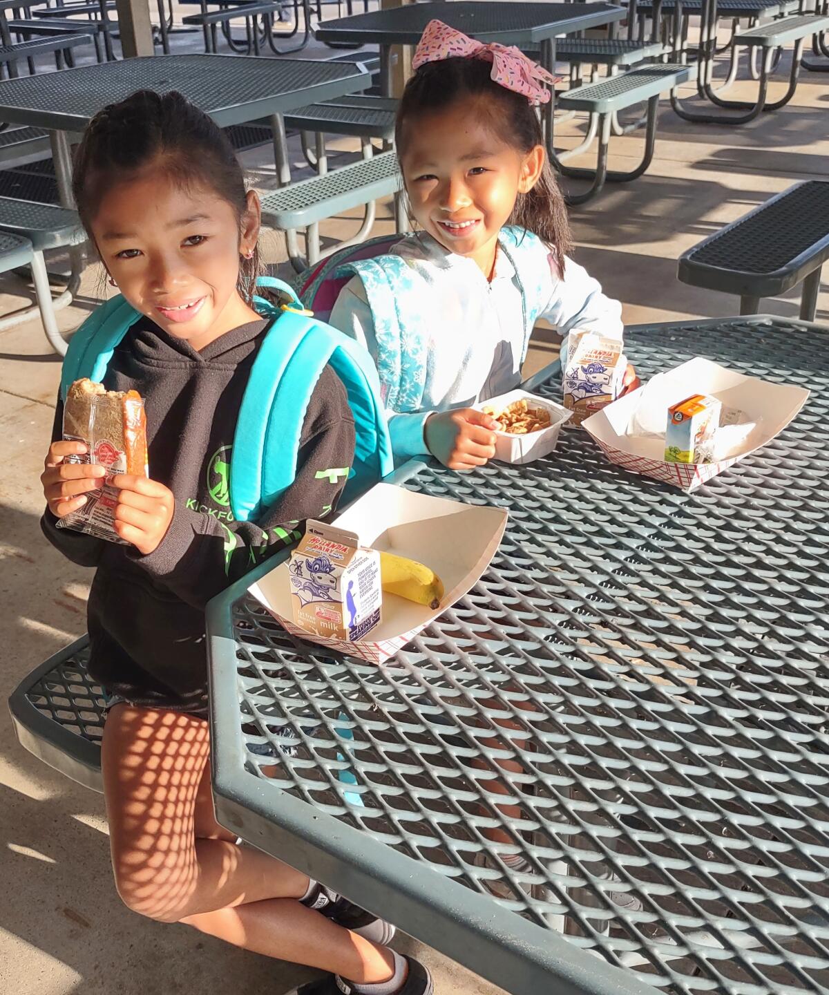 Leona Lansang, 7, left, and her sister Lillian Lansang, 6, have breakfast together at Garden Road Elementary School.