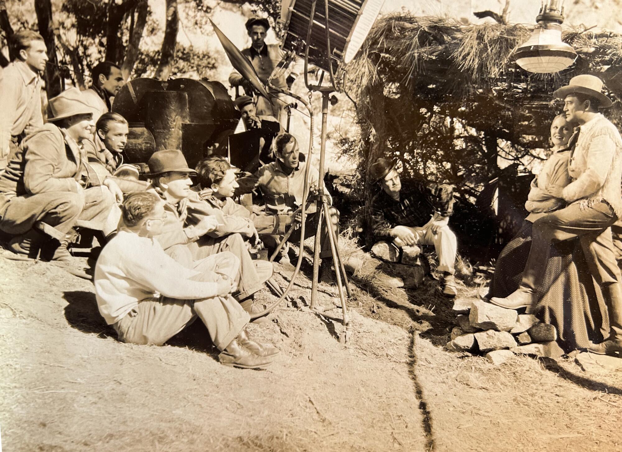 People sit on the ground in a vintage photo from a movie set