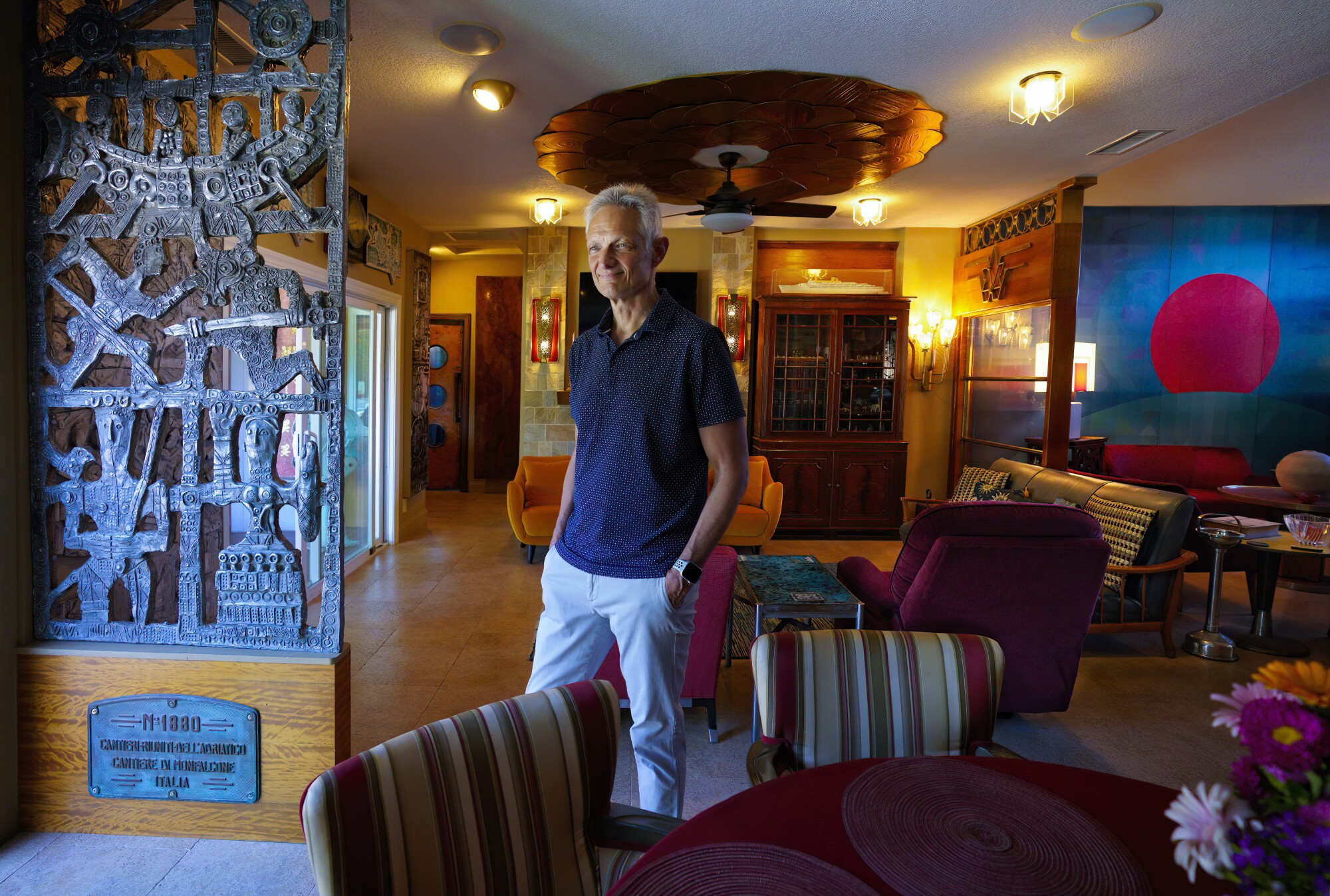 Peter Knego stands among his extensive collection of artwork, furniture and decor 