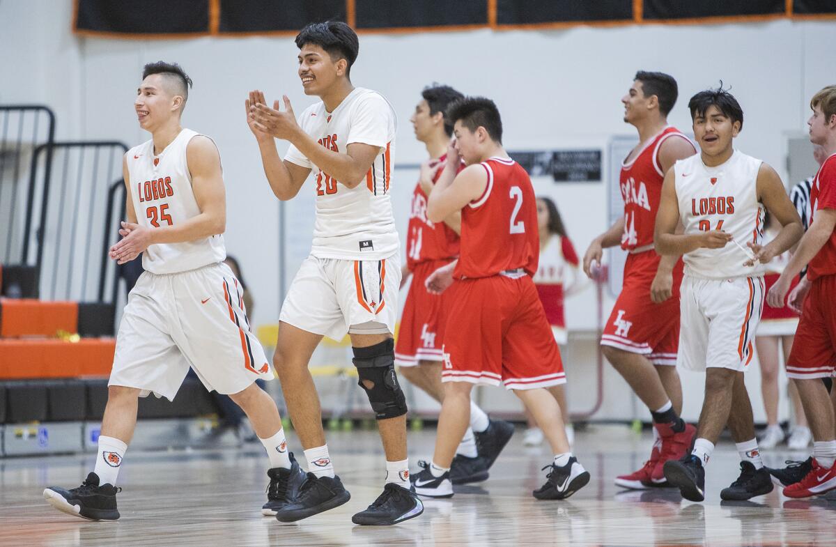 Los Amigos' Michael Valencia (35), Brian Pacheco (20) and Marco Vasquez (24) celebrate after beating Loara in a Garden Grove League game on Tuesday in Fountain Valley.