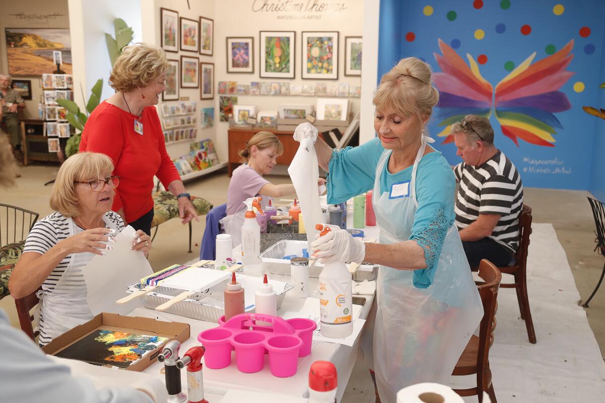 Artist Sandy Clark, far right, joins others during a "pour paint" workshop at the Laguna Art-A-Fair show on Friday.