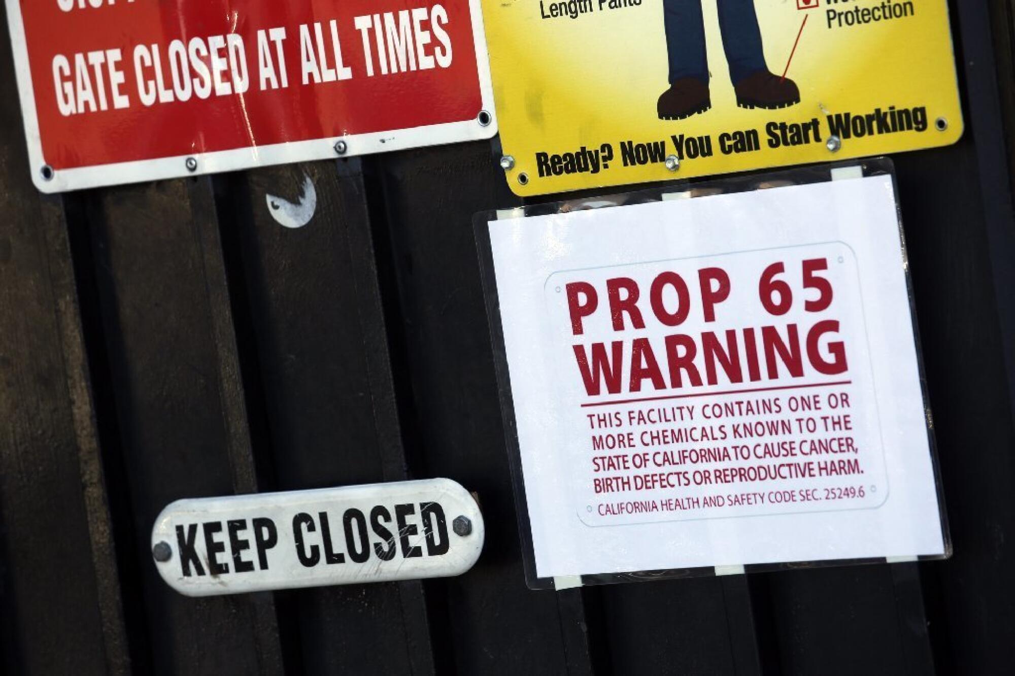 A Proposition 65 notice is one of several warning signs posted on a gate at Aerocraft Heat Treating in Paramount.