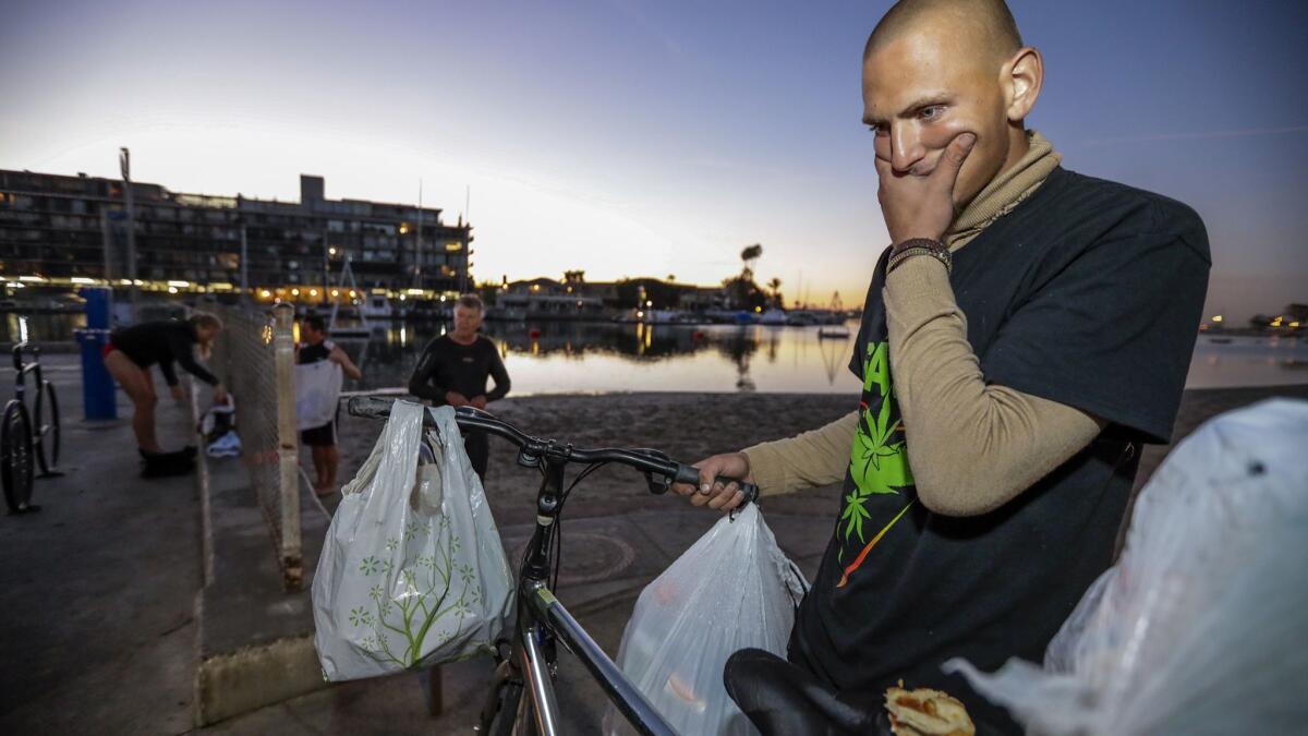 Chase Grant, 20, who has been living on the streets for seven months, collects recyclables in Belmont Shore, where residents blaming crime on the homeless population went on an early morning patrol march Friday.