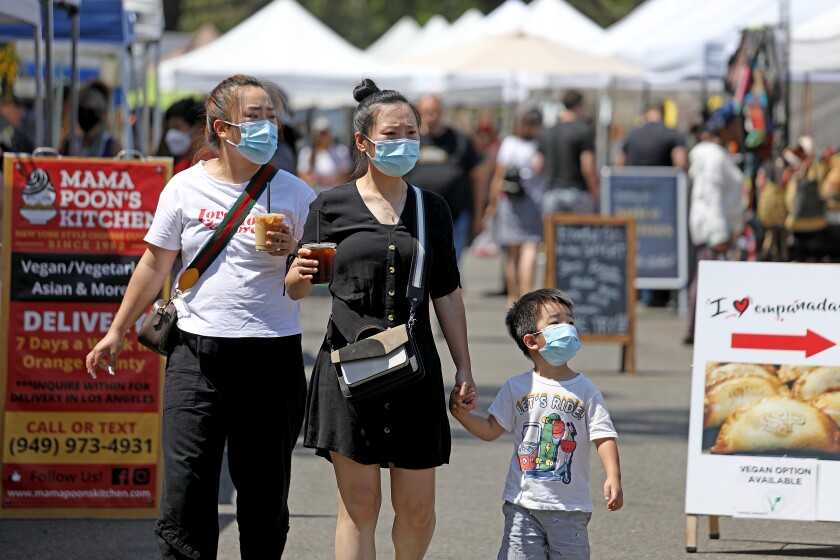 A masked family shops at an outdoor farmers market.