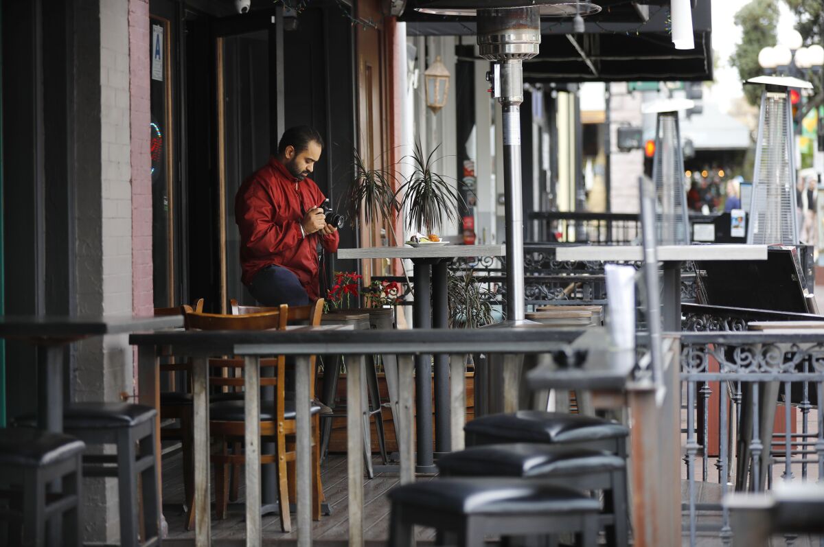 Surinder Singh, owner of Urban India restaurant in the Gaslamp Quarter, takes a photo of a dish to kill time with no customers in sight on March 16, 2020. The popular part of Downtown San Diego was all but empty even before quarantine rules were issued.