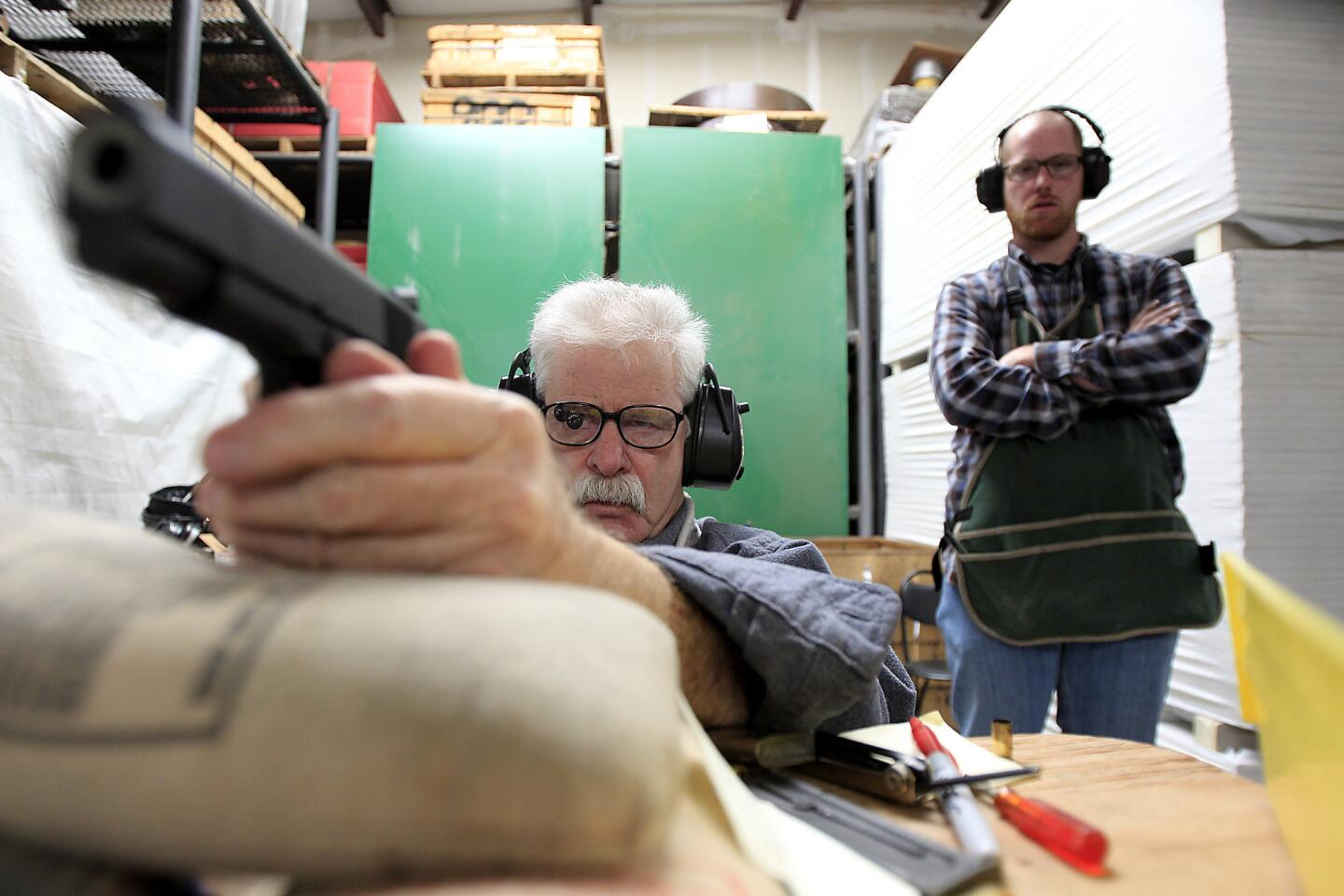 Gunsmith Terry Tussey, left, takes aim on a target before test-firing a 1911 Colt pistol as apprentice Kevin Smith looks on. Tussey test-fires all of the guns he repairs at his shop in Carson City, Nev.