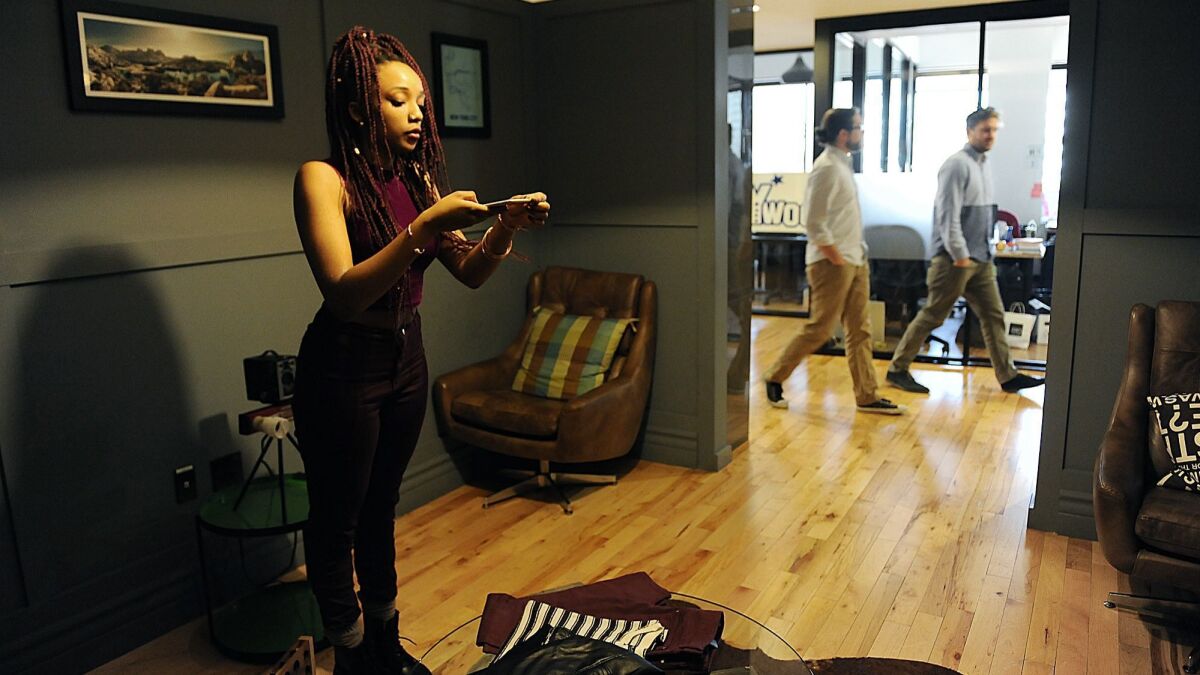 Khairah Cook, an intern with Hollywood Closet Rentals, takes photographs of clothing inside a lounge at a WeWork co-working office space in Hollywood in 2014.