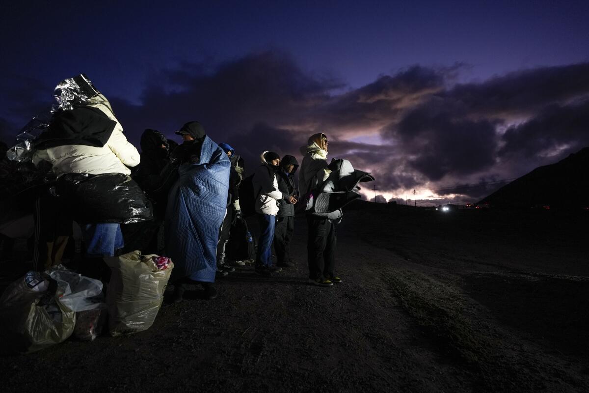 Migrants lined up and wrapped in blankets 