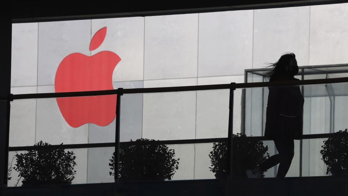 A woman runs past an Apple logo