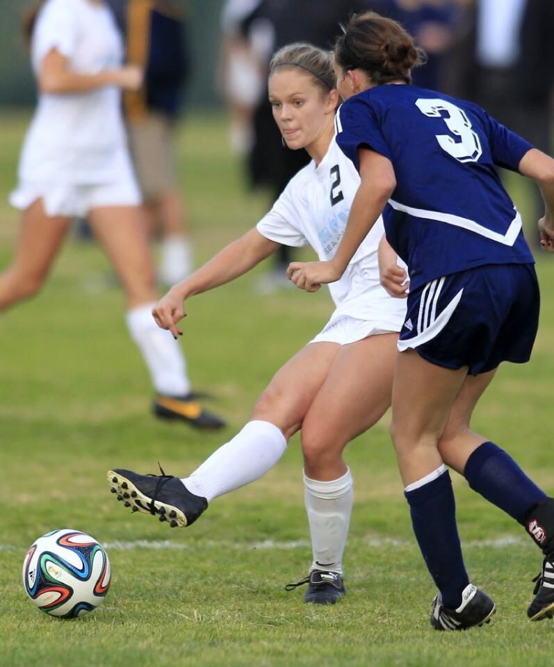 Corona del Mar High's Miranda Stiver (2) passes the ball defended by Newport Harbor's Emily Gess (3) during the first half in the Battle of the Bay match on Tuesday.