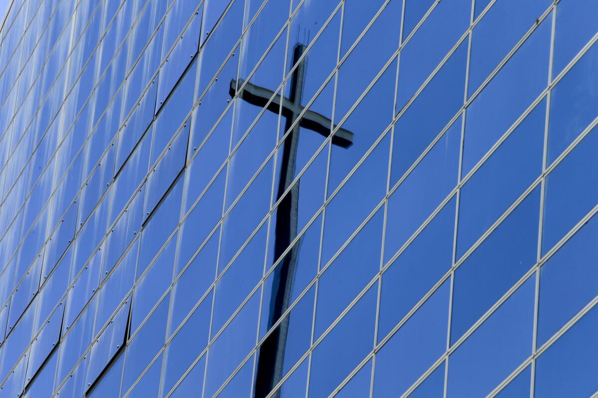 The giant 90-foot cross atop Tower of Hope is reflected in the windows of the Christ Cathedral, which will soon close for construction.