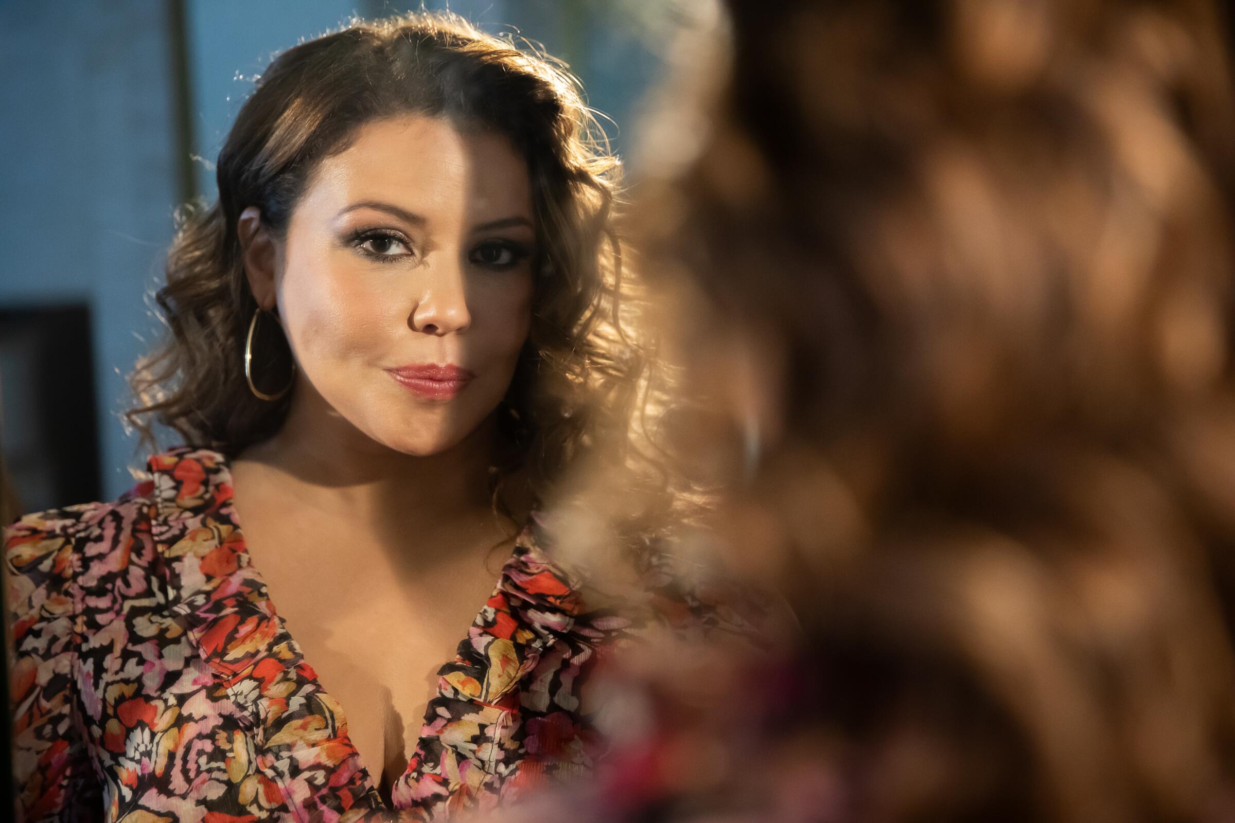Actor Justina Machado photographed looking at the camera in a mirror