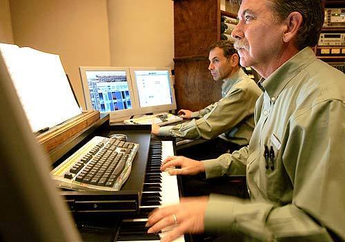 Golden Era Productions music director Peter Schless watches a video monitor while scoring a Scientology production with assistant Neil Kunen (background). Schless co-wrote the 1982 hit "On the Wings of Love.