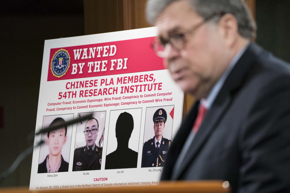 U.S. Atty. Gen. William Barr displays photos of the people indicted in the Equifax hack.