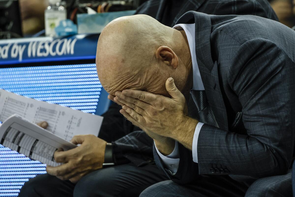 Mick Cronin covers his eyes with his hands.