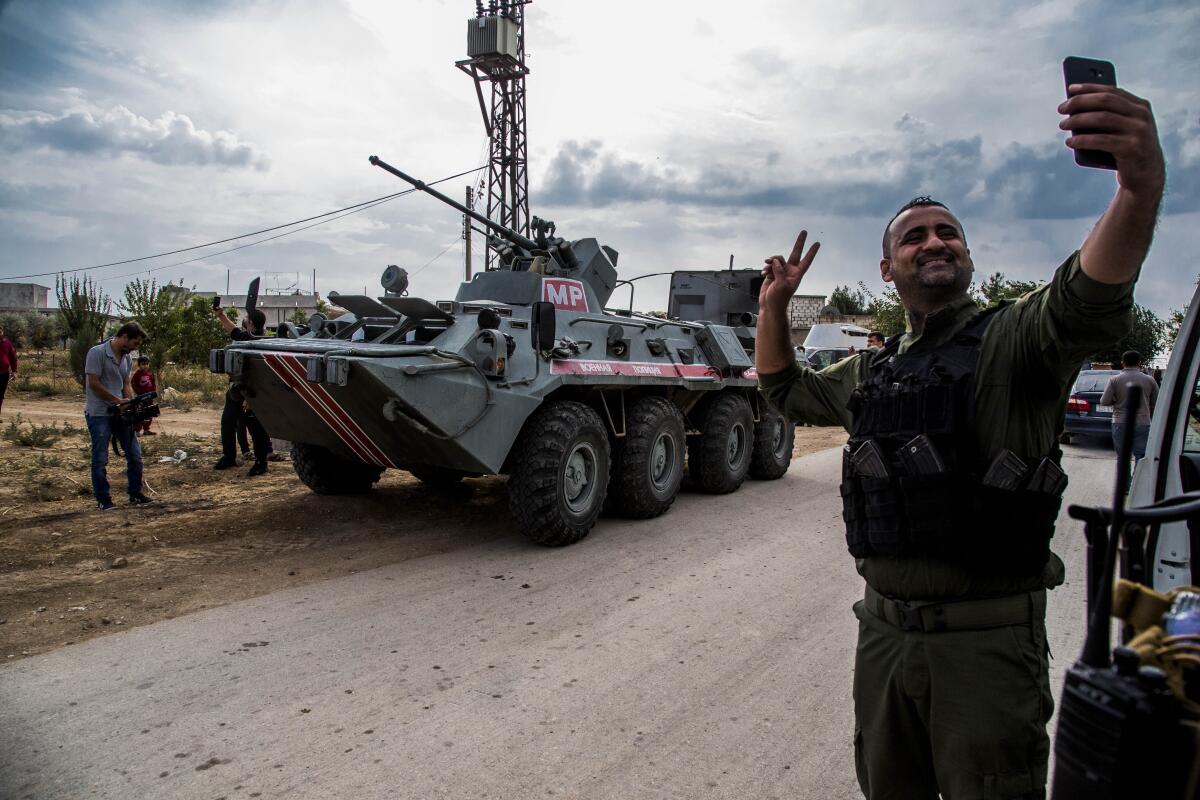 A member of the Kurdish Asayish, or the Internal Security Forces, takes a selfie by an Russian military vehicle during a patrol near the Syrian-Turkish border.