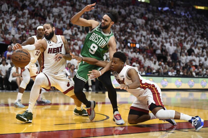 El alero del Heat de Miami Caleb Martin pelea para alcanzar el balón frente a su compa?ero Kyle Lowry y el base de los Celtics de Boston Derrick White el 27 de mayo del 2024. (AP Foto/Michael Laughlin)