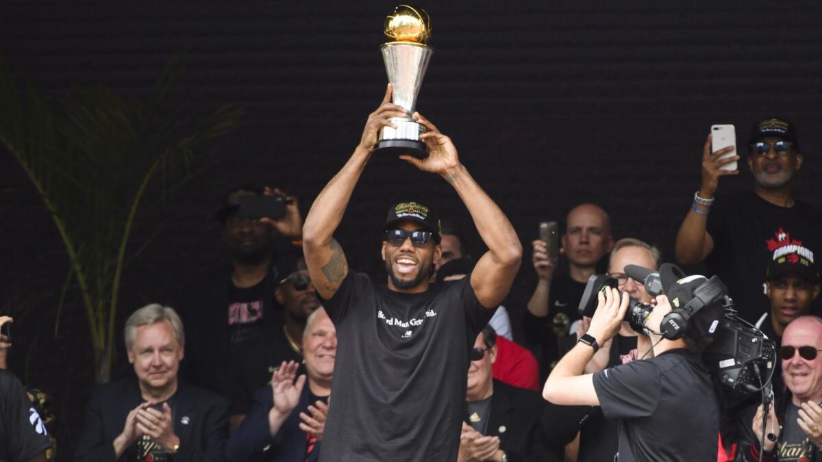 Toronto Raptors forward Kawhi Leonard hoists the MVP trophy next to teammates during the team’s NBA championship parade in Toronto on Monday.