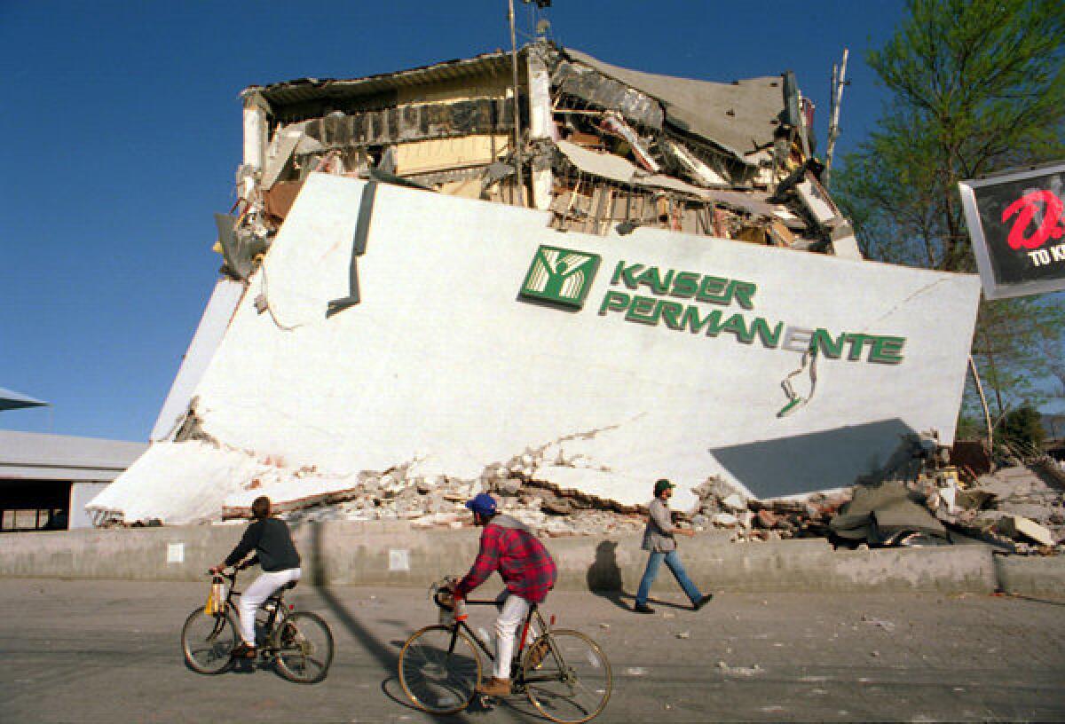 Cyclists ride past the remains of a collapsed Kaiser Permanente clinic and office building.