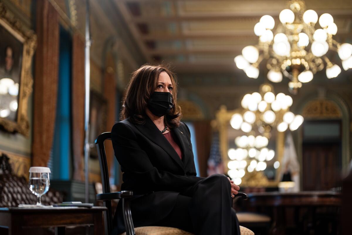 Kamala Harris sits in a chair wearing a face mask