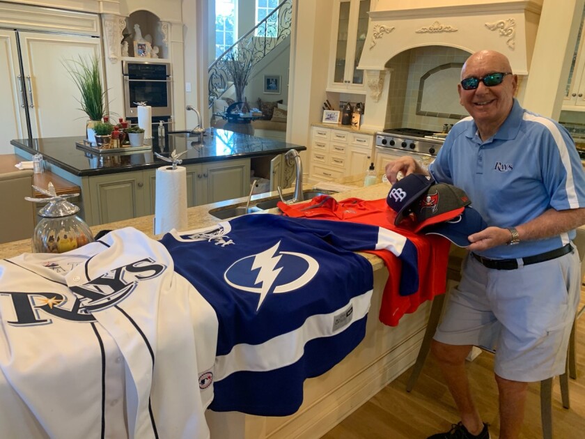ESPN college basketball analyst Dick Vitale displays his Tampa Bay jerseys and hats on his kitchen counter.