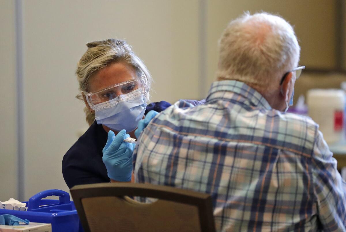 Hoag vocational nurse Kristina Kuzma, left, administers a vaccine shot.
