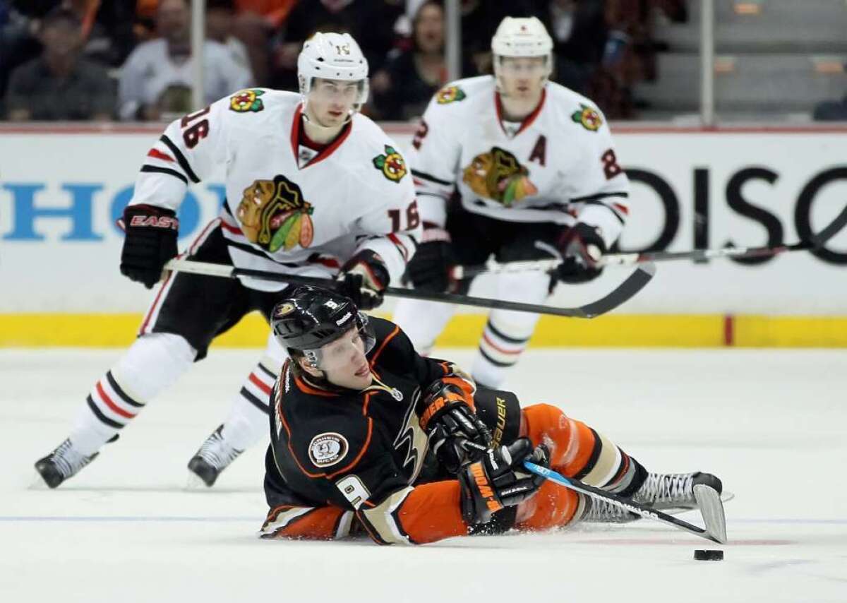Ducks forward Bobby Ryan tries the handle the puck from the ice while Blackhawks center Marcus Kruger skates after him in 2012.