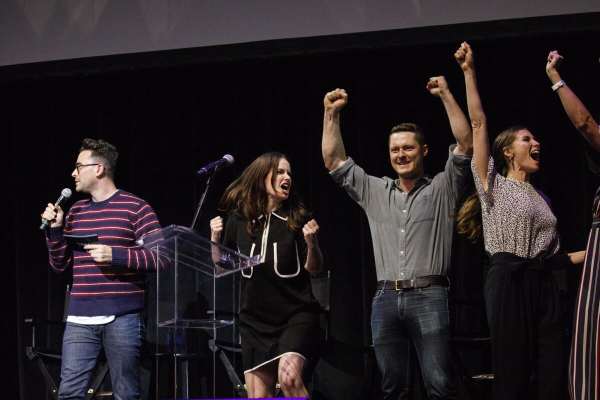 Actor Dan Levy prepares to read a question as actors Emily Hampshire, Noah Reid and Sarah Levy, right, react to scoring a point during the audience trivia game portion of Schitt's Creek Live.