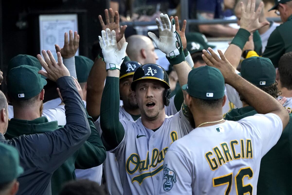 Oakland Athletics' Stephen Piscotty, center, is congratulated in the dugout after his three-run home run off Chicago White Sox starting pitcher Lance Lynn during the second inning of a baseball game Friday, July 29, 2022, in Chicago. (AP Photo/Charles Rex Arbogast)