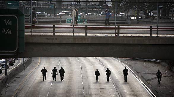 Los Angeles police officers comb the southbound lanes of the 101 Freeway in downtown Los Angeles for evidence as they investigate the shooting of a man driving a Bentley. The driver was hit several times and was hospitalized in critical condition.