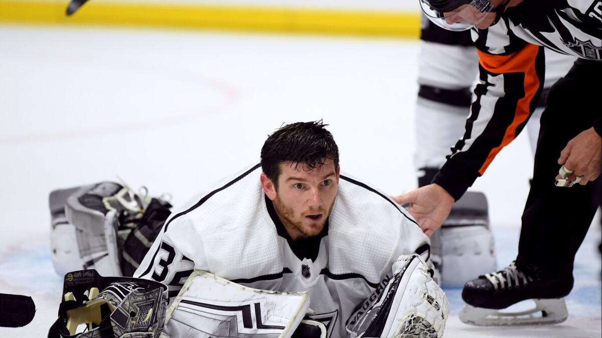 Kings goalie Jonathan Quick is checked on by referee Brian Pochmara after losing his face mask during the third period in a 2-0 win over the Carolina Hurricanes at Staples Center on Sunday.
