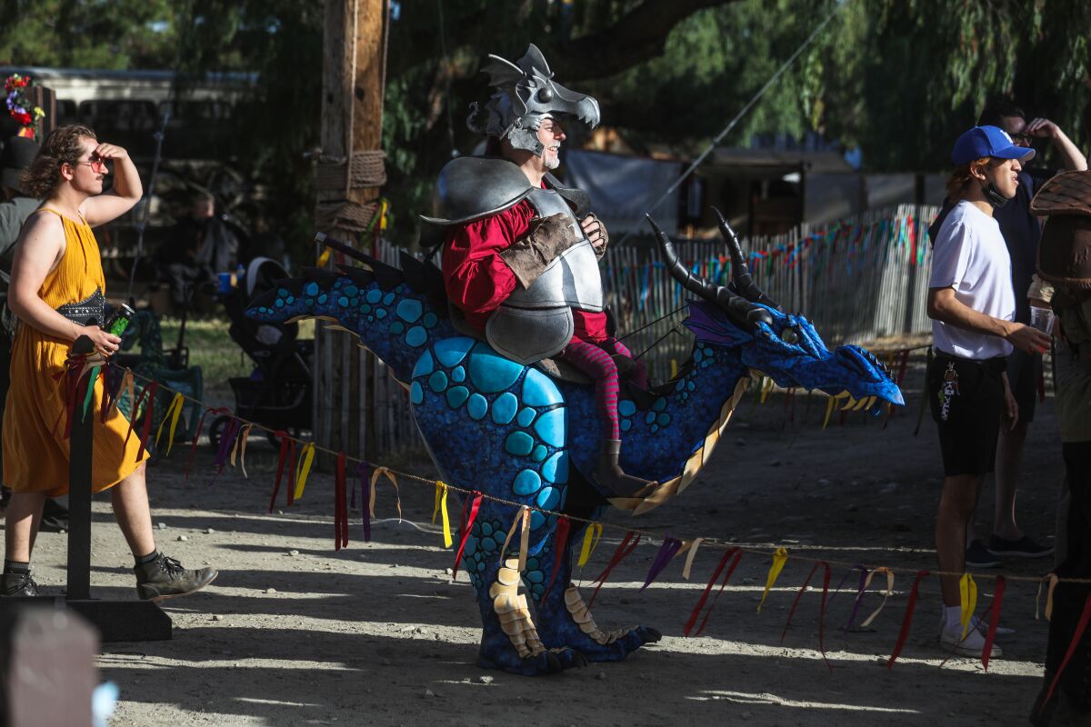 A man wearing a costume that makes it appear as if he's riding a dragon.