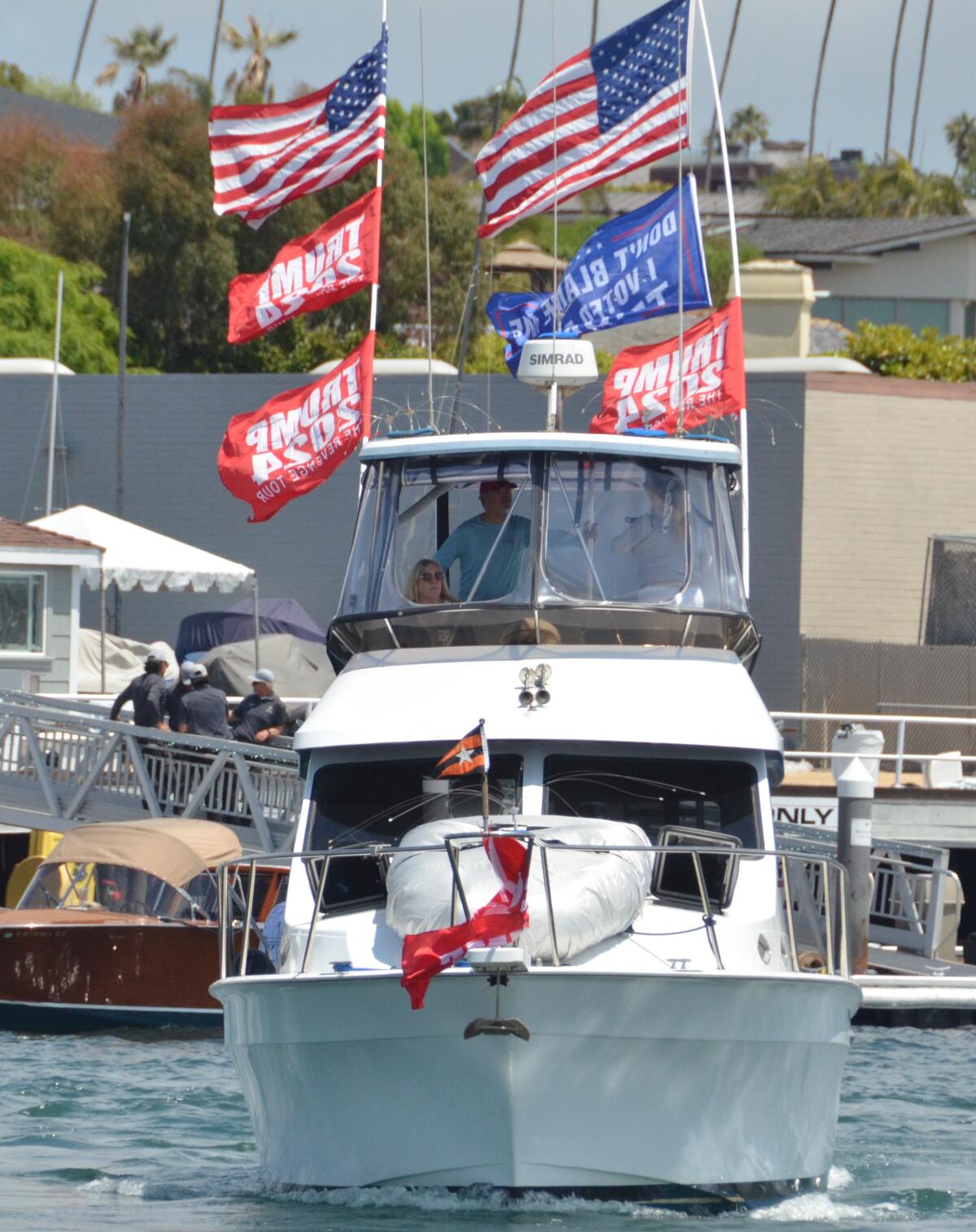 Flags flapped in the breeze atop the flybridge as a boat cruised in the Trumptilla parade in Newport Harbor.