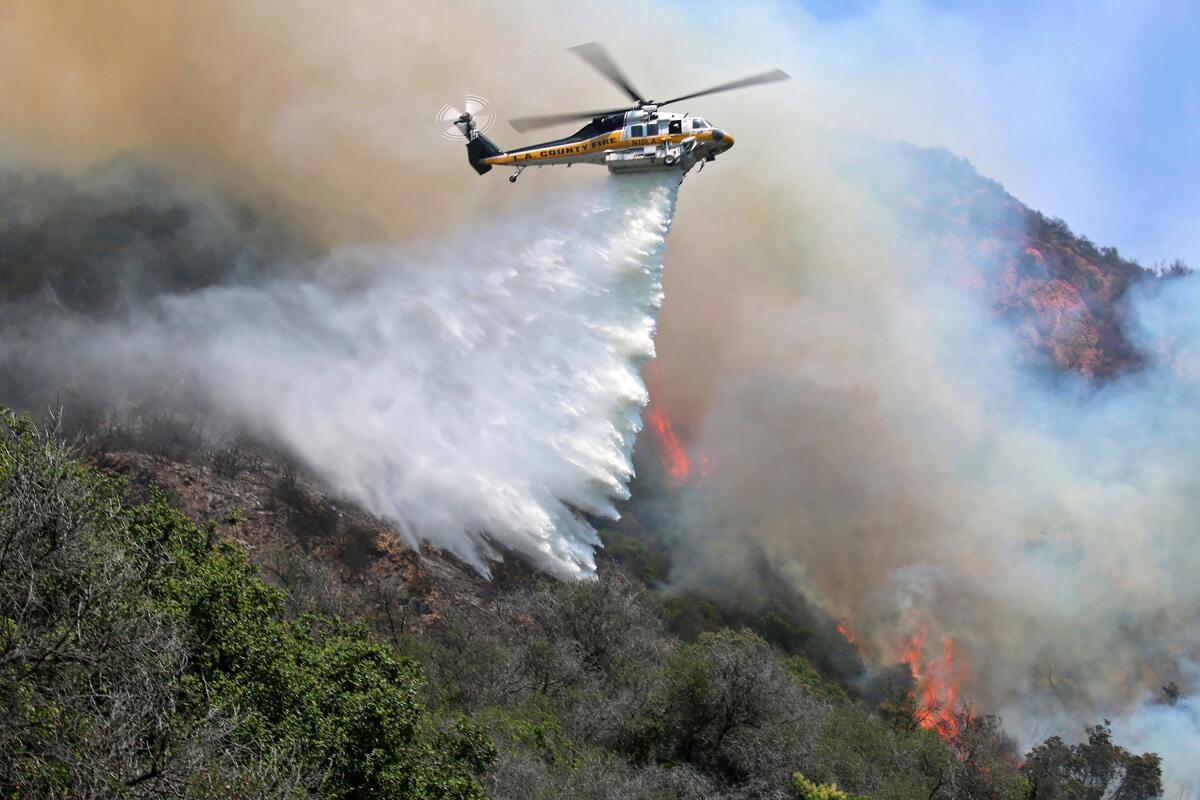 A helicopter drops water onto a fire in Topanga Canyon.